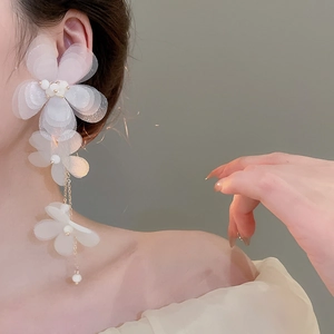Detailed view of chiffon flower earrings with tassels and pearls worn by a model