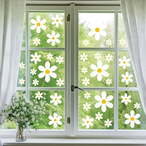 Detail of white daisy window stickers with yellow centers on glass with a garden background