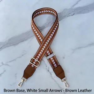 Detail of adjustable brown fabric guitar bag strap with white arrow patterns and gold hooks