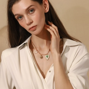 Detail of 18K gold-plated necklace with three distinct heart-shaped charms on a model