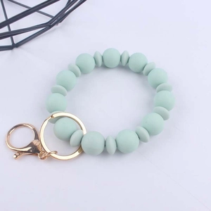 Dettaglio delle perle in silicone verde chiaro e anello in metallo dorato del portachiavi