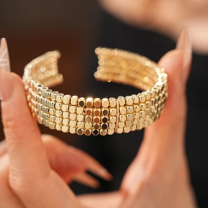 Détail de la texture perlée dorée multicouche et de la finition polie du bracelet manchette