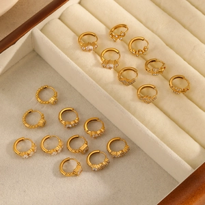 Golden stainless steel huggie earrings with various cubic zirconia stone shapes on velvet