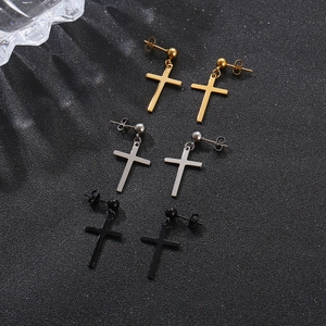 Detailed close-up of cross pendant earrings in gold, silver, and black polished steel