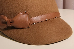 Close-up of brown wool felt equestrian hat with rhinestone bow and leather strap