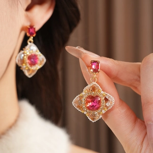 Macro view of vintage style gold-toned earrings featuring a red square gemstone and pearls