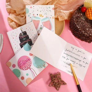 Flat lay of birthday greeting cards with handwritten wishes on a soft pink background