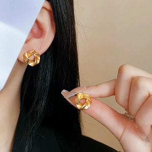 Close-up of matte gold geometric twisted earrings with elegant brushed metal texture