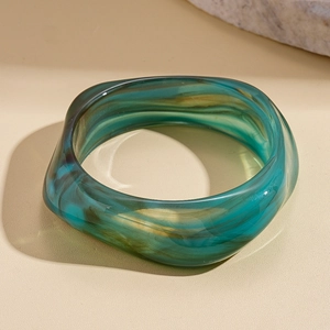 Close-up of marble pattern acrylic resin bangle with emerald green and brown fluid textures