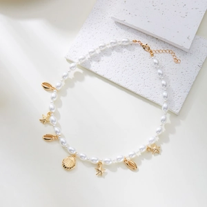 Chic ocean pearl necklace with gold seashell and starfish charms on a white stone base