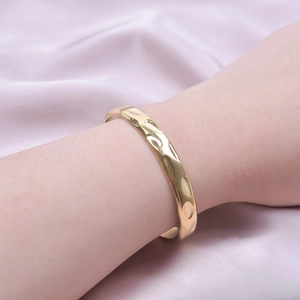 18k gold plated stainless steel cuff bracelet with hammered texture on silk background