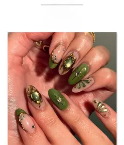 Detail of 3D almond fake nails with emerald green cats eye, gold relief and rhinestones