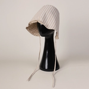 Detail of baby striped sun hat with chin strap and soft beige vintage cotton texture