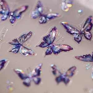 Macro shot of iridescent purple and blue butterfly nail stickers with glitter finish
