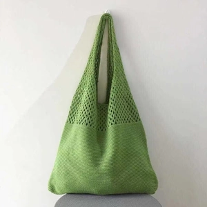 Detail view of the green hollow-out knit texture and woven handle on the tote bag
