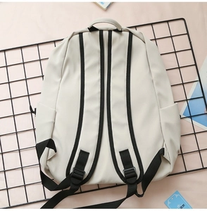 Detail view of cream canvas backpack with contrasting black straps on mesh grid