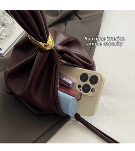 Detail view of burgundy pleated bucket bag showing interior storage for phone and lipstick