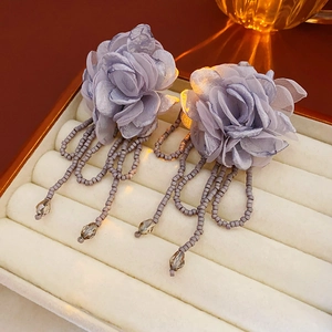 Detailed view of light purple fabric flower earrings with grey beaded fringe tassels