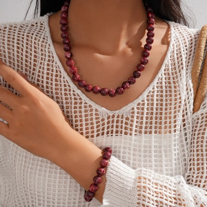 Detail of burgundy acrylic beaded necklace and bracelet set with marbled texture