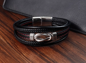 Detail eines mehrlagigen schwarzen Lederarmbands mit roter Naht und silbernem Magnetverschluss