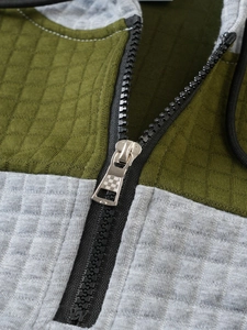 Close-up of olive green waffle fabric and black zipper detail on hooded sweatshirt