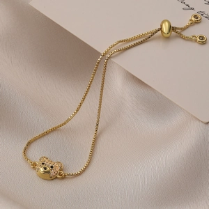 Adjustable gold plated bear charm bracelet with sparkling zircons on champagne silk