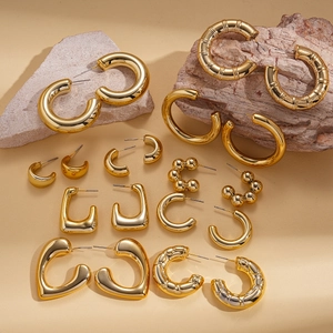 Detailed arrangement of gold geometric earrings set on natural stone background