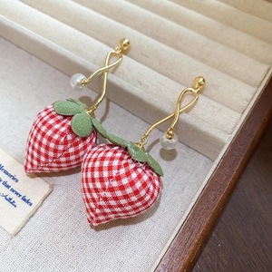 Macro shot of red plaid fabric strawberry earrings with green felt leaves and gold pearl hooks
