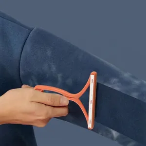 Manual lint remover for clothes showing orange T-shape tool on blue fleece fabric