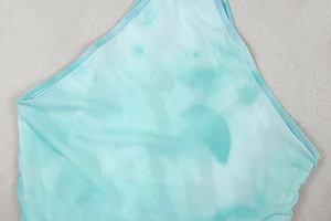 Macro detail of mint green tie-dye texture and stitching on thin breathable fabric