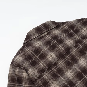Close-up detail of the brown plaid pattern and stitching on the shirt collar and shoulder