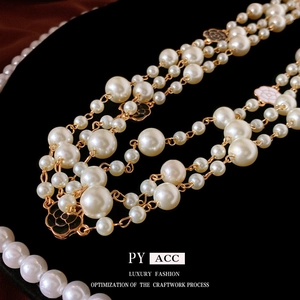 Multi-layer camellia baroque pearl necklace with gold chain on black velvet background