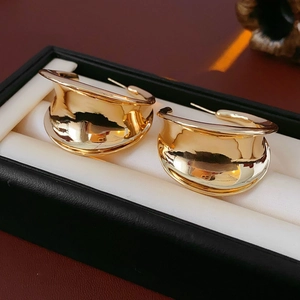Detailed view of large gold wide-surface C-shaped earrings in a premium jewelry box
