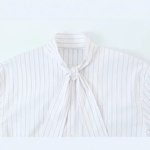White and brown striped blouse featuring a tie-neck design and delicate button detail