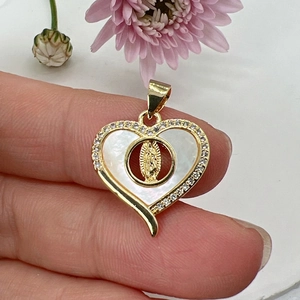 Macro view of gold heart pendant with white mother of pearl and Virgin Mary relief