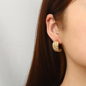 Chic 18k gold plated stainless steel twisted C-shape hoop earring worn by a model
