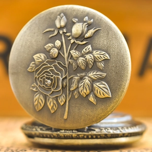 Close-up of vintage bronze pocket watch featuring detailed rose flower embossed design