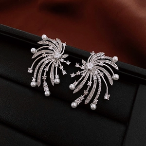 Macro detail of silver starburst earrings with white cubic zirconia and pearls on black leather