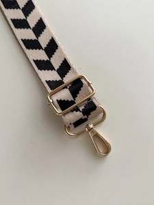 Detail of adjustable 38mm canvas bag strap with beige and black chevron pattern and gold clips