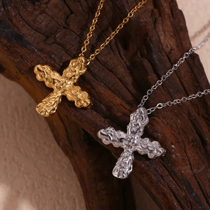 Macro detail of gold and silver cross necklaces with irregular hammered texture on wood