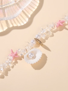 Detail of seashell charm with embedded pearl on beach style beaded bracelet
