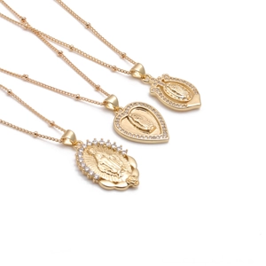 Detailed view of three gold-plated Virgin Mary heart pendants with sparkling crystals