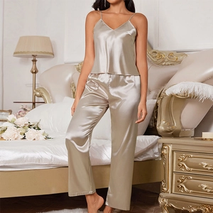 Women's 2-piece champagne satin pajama set with camisole and long pants in luxury bedroom