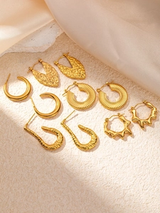 Detailed set of 5 golden geometric stud earrings on a textured stone surface display