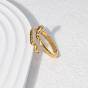 Macro shot of gold snake-shaped adjustable ring with scale texture on white tray