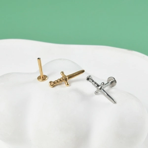 Detailed view of three stainless steel sword-shaped lip studs in gold and silver finish