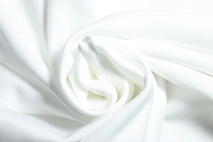 Nahaufnahme der weichen Textur und des seidigen Glanzes des weißen Strickkleid-Stoffes