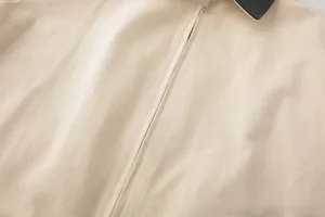 Detail of beige jacket canvas texture with black collar contrast and silver metal zipper