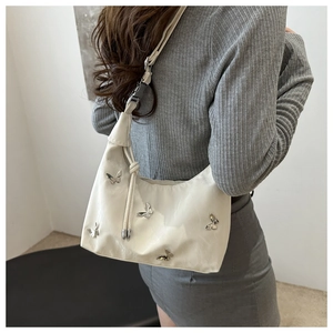 Detail of cream shoulder bag with silver metallic butterflies and adjustable strap