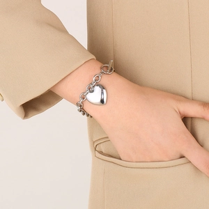 Detail of silver heart pendant bracelet with OT toggle clasp worn by a fashion model